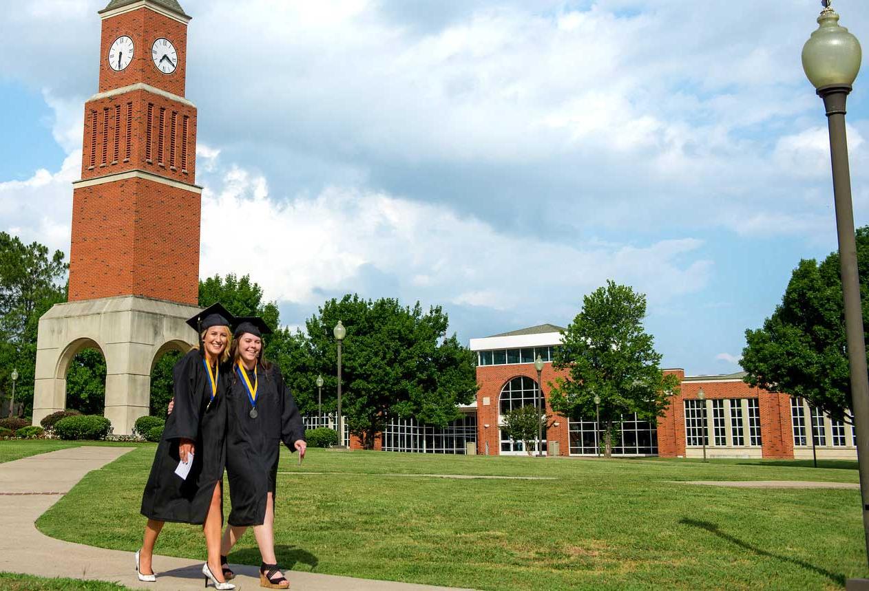 两个即将毕业的女生站在纳瓦罗校区的钟楼前.